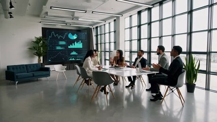 Financial professionals collaborating over digital market trends, reviewing cryptocurrency performance data on expansive monitor in contemporary workspace, representing global investment analysis - Powered by Adobe