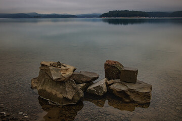 misty morning on the lake with stones in the foreground