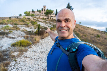 Man taking a selfie pointing an old hermiatge on background, in Bocairent, Comunidad Valenciana...