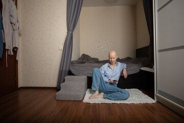 Cancer patient sitting on floor at home using smartphone for communication and online support...