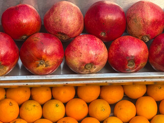 Fresh pomegranates and oranges arranged in neat rows at a market stall. Agriculture, nutrition, and fruit trade with colorful presentation and natural abundance.