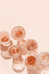 Wine Glasses of rose wine on pink background, sun flare and reflection from sunlight. Aesthetic...