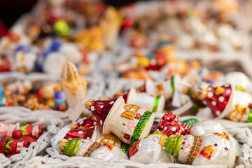 A festive assortment of glass Christmas ornaments featuring snowmen, mushroom houses, and bright holiday colors displayed in woven baskets.