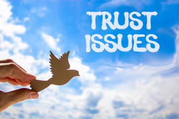 Trust issues symbol. Concept word Trust issues on beautiful blue sky. Businessman's hand with...