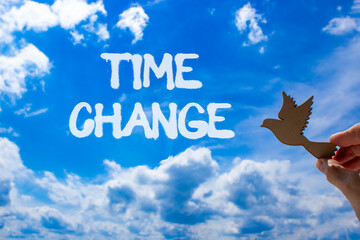 Time change symbol. Concept word Time change on beautiful blue sky. Businessman's hand with wooden...