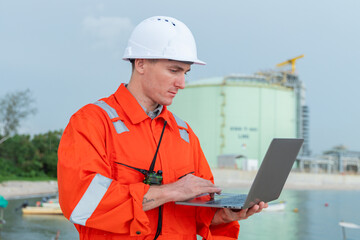 Engineer at LNG Facility Holding Laptop