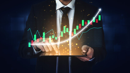 A businessman dressed in a suit holds a tablet displaying stock market data visualization. The...
