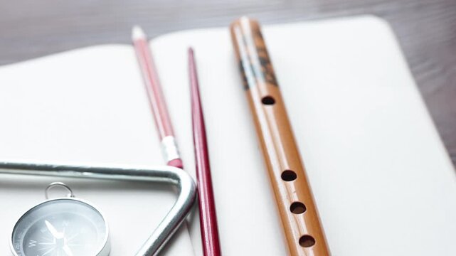 Essential Study Supplies: Notebook, Pen, Bell, Brush, and Flute on a Wooden Desk
