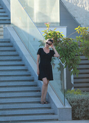 portrait of tall slim brunette woman in black fashionable short dress at resort