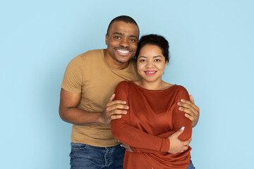 Fototapeta premium Smiling African American couple standing close together in studio. Portrait of young man and woman in casual clothing symbolizing love, bonding, and positive lifestyle.