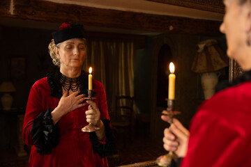 Victorian lady in red bustle dress with burning candle
