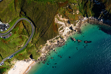 Aerial top down view of winding road with a car and a parking lot at Keem Beach on Achill Island in Ireland