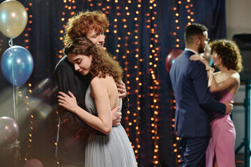 Caucasian teenage boy and Caucasian teenage girl embracing while dancing closely at formal event,...
