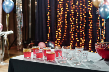 Table displaying several glasses with pink beverages and lemon slices arranged beside empty glasses at festive party setting