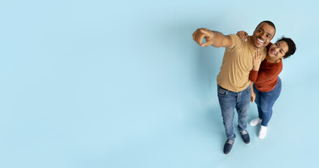 Above view of young black couple pointing at copy space, romantic african american spouses demonstrating free space for your advertisement, panorama