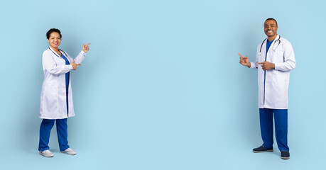 Two smiling African American doctors pointing across empty studio space in medical uniforms. Healthcare teamwork, confidence, and professional guidance concept illustration