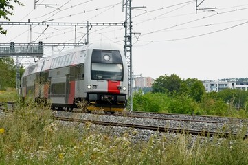 The modern high-speed train moves along the rails on a summer day