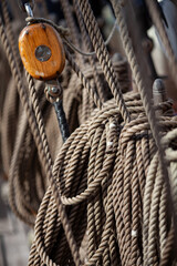 Traditional wooden ship pulley block with thick coiled ropes. Sailing rigging detail for nautical and maritime themes.