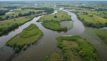 Aerial view of a river meandering through a green landscape with islands and fields under an overcast sky.