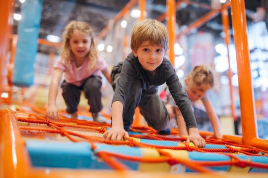Kids are actively climbing and navigating a vibrant obstacle course inside an indoor playground, enjoying physical activity and social interaction with peers