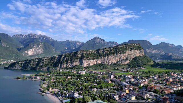 Stunning 4K aerial drone footage of Nago-Torbole and Torbole sul Garda on the northern shore of Lake Garda, Italy. Scenic view of the colorful town, mountains, beach, sailing boats