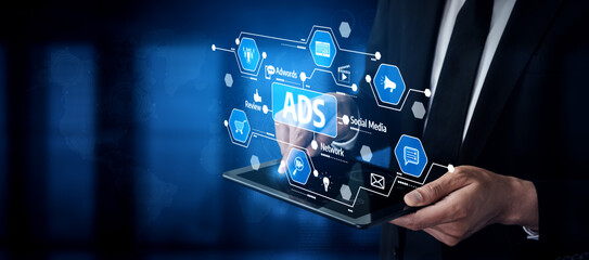 A businessman engages with a digital tablet showcasing various icons related to advertisements and social media, exemplifying the fusion of technology and marketing in a corporate setting. Tessel