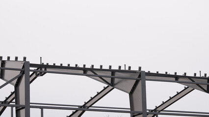 Metal construction, in the photo the structure of the building frame made of metal beams against the background of a gray sky