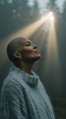 A woman with short hair is wearing a gray sweater and looking up at the sun. Concept of peace and tranquility as the woman takes a moment to appreciate the beauty of the sun shining through the trees