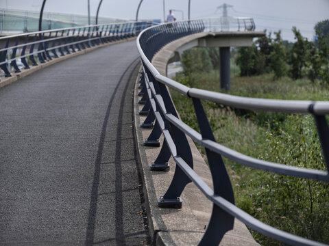 Modern bridge roadway showing curved design with protective railings and urban setting - Powered by Adobe