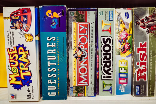 A collection of classic board games lined up on a white shelf. For Editorial Use Only.