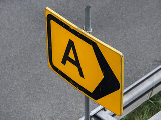 Detailed view of weathered yellow highway sign showing letter A with mounting hardware