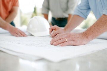 Three men are working on a drawing of a building