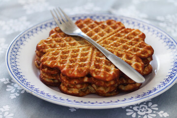 Waffles on a plate with a fork on top. 