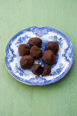 Chocolate truffles on a blue vintage plate placed on a green table