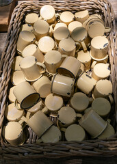 Close up on large amount of metal enamel coated mugs in a basket.