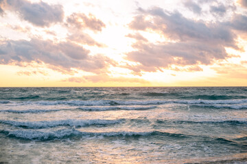 Soft waves roll onto the shore under a soft, overcast sky, creating a sense of calm and tranquility