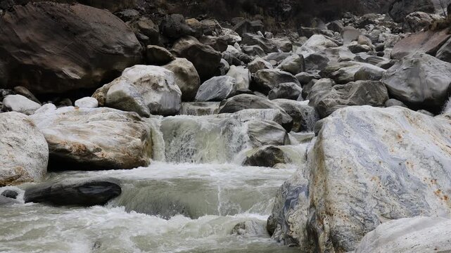 Real time video of waterfall stream falling from the cliff. Gray rocks in the river cascade of a high waterfall