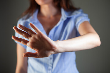 Close-up of woman showing stop gesture against grey background. Focus on hand