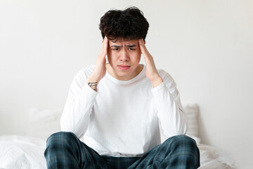Health problems, symptoms of illness, suffering from migraines. Sad millennial asian man sitting on...