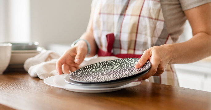 Woman Placing Plates On Table - Powered by Adobe