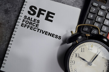 Concept of SFE - Sales Force Effectiveness write on book isolated on Wooden Table.
