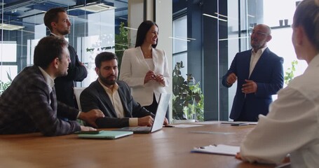 Senior leader talking on business training and briefing meeting, speaker explaining strategy presentation to project team in modern glass office. Colleagues listening speech at boardroom table - Powered by Adobe