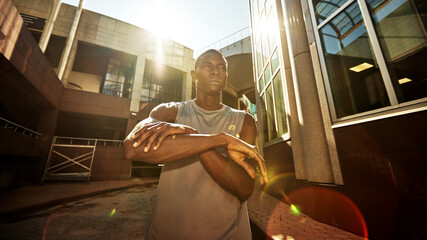 Obraz premium Young man stretching outdoors with urban backdrop on a sunny day