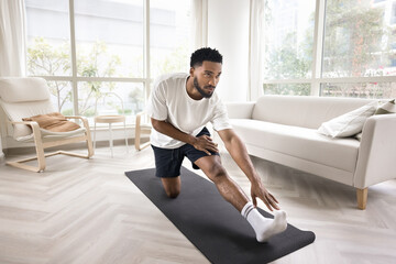 Young man practice stretching exercises on yoga mat at home