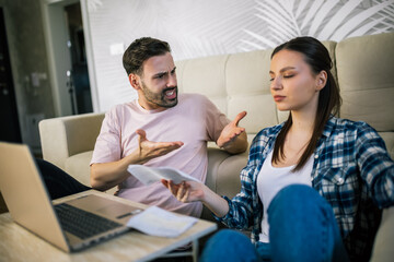 Stressed couple arguing over unpaid bills at home