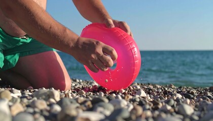 Man inspecting a pink inflatable ring on the beach