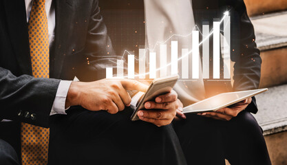 Two business professionals engage in data analysis using mobile devices, with a financial growth graph overlay. This modern setting highlights collaboration and strategic planning. Impute