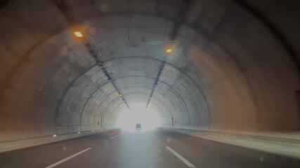 A car speeding through a tunnel on the highway and the moment it exits the tunnel. - Powered by Adobe