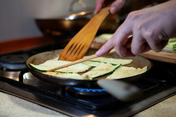 Fresh zucchini slices being grilled on frying pan