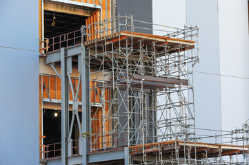 Close-up of scaffolding and structural steel framework on the exterior of a large data center campus under construction, highlighting infrastructure for technology operations